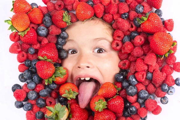 Summer fruits. Berries with kids face close-up. Top view of child face with berri. Berry set near kids face. Cute little boy eats berries. Kid eating vitamins. Close up kids face