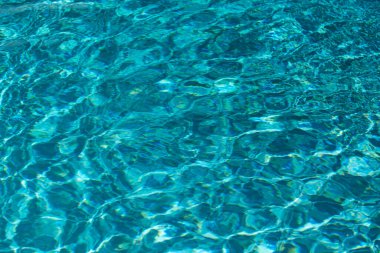 Yüzme havuzundaki mavi suyun arka planında güneş yansıması, havuzda dalgalı su dalgaları. Temiz su arkaplanı