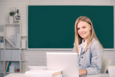 Ders çalışan, masada oturan ve sınıfta deftere yazı yazan gülümseyen genç üniversite öğrencisinin portresi