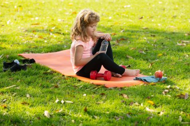 Sporcu çocuklar. Çocuk sağlıklı yiyecekler yiyor, egzersizden sonra su içiyor. Fitness, sağlıklı meyveler ve aktif yaşam tarzları