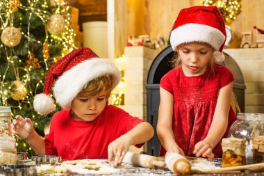 Noel Baba için kurabiye. Sevimli küçük erkek ve kız ikizler mutfakta Noel kurabiyeleri hazırlıyorlar. Komik çocuklar Noel Baba için kurabiye yapıyor.