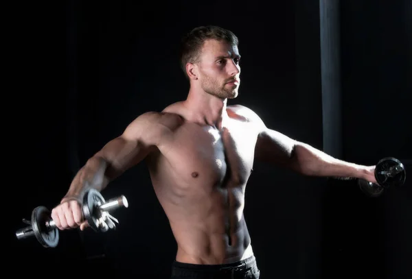 スポーティな胴 ダンベルの男 筋肉質の男がクロスフィットを行う スタジオで働いている若い男 運動中のアスリートマン — ストック写真