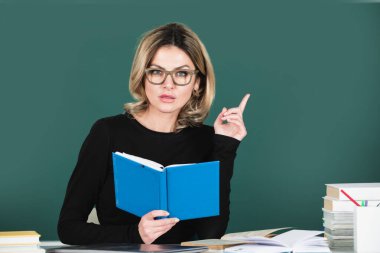 Üniversitede ya da lisede masada çalışan öğretmen ya da kadın öğretmenin portresi. Sınıfta okuyan genç bayan öğrenci. Konsept çalış