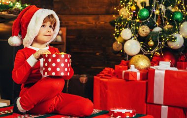 Çocuk Noel Baba kıyafetleri giyiyor, yeni yılı bekliyor. Çocuklar için Noel hediyeleri