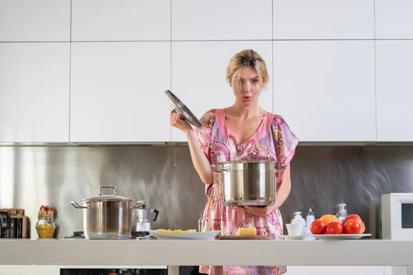 朝のモダンなキッチンで鍋料理を持つ女性 居心地の良いキッチンでかなり若い女性料理の肖像画 モダンなインテリア キッチン用の家具 — ストック写真
