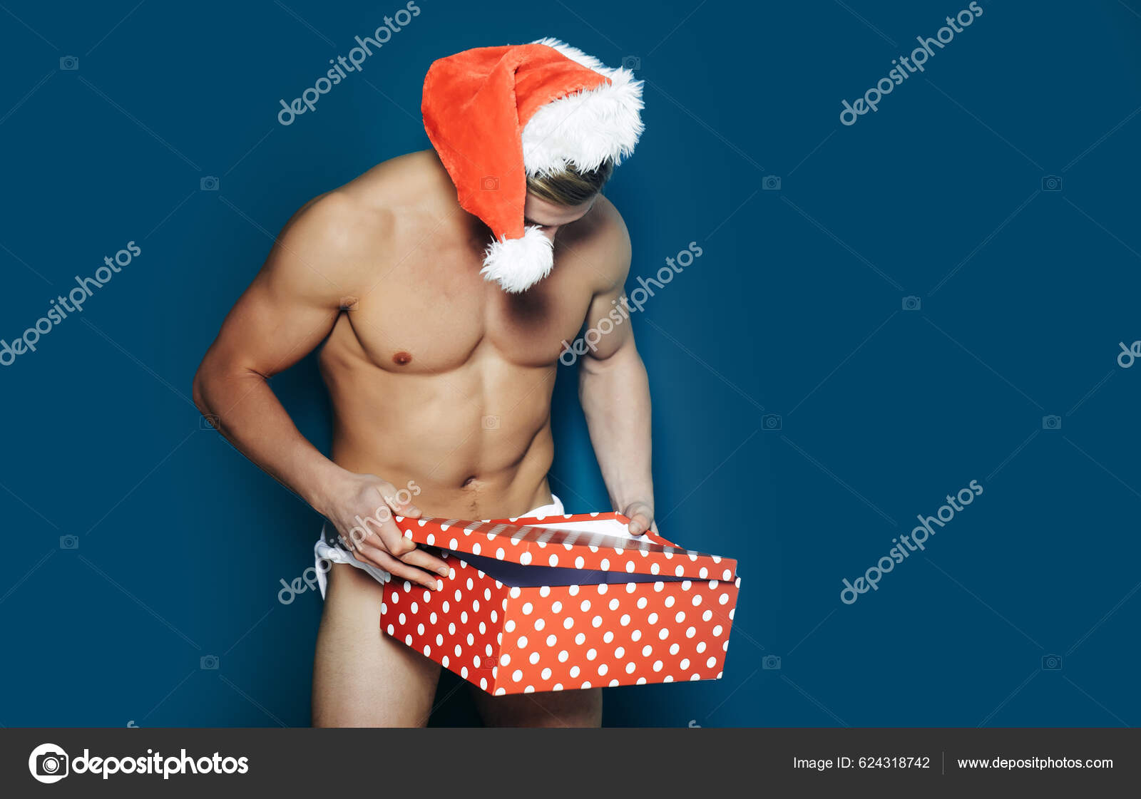 圣诞节性感男人戴着桑塔帽的年轻人圣诞节时的肌肉人圣诞老人肌肉发达圣诞派对和性爱游戏漂亮性感的蓝底桑塔