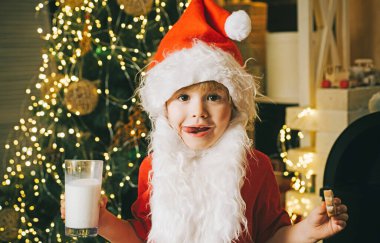 Noel Baba çocuk kurabiye yiyor ve süt içiyor. Noel yemeği ve içkisi. Küçük Noel Baba 'nın portresi. Camdan süt içiyor ve elinde kurabiye tutuyor.