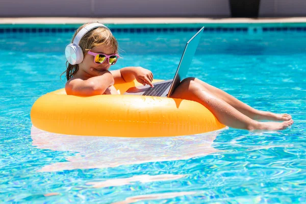 快乐的小男孩在网上学习电脑笔记本电脑 孩子们在游泳池里用电脑放松一下 休息在五彩缤纷的充气环上 暑期旅行和商业概念 — 图库照片