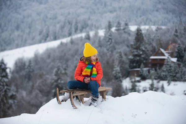男の子はそりに乗るのを楽しんでいます そりの上の子供 子供は雪の中で外で遊ぶ クリスマスの時間 冬の楽しい子供の活動 — ストック写真
