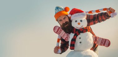 Noel kardan adamı ile heyecanlı genç bir adam. Kışın arka planda kardan adamla harika bir adam. Kış bayrağı için kardan adam. Noel ve yeni yıl kar konsepti, kış mevsimi