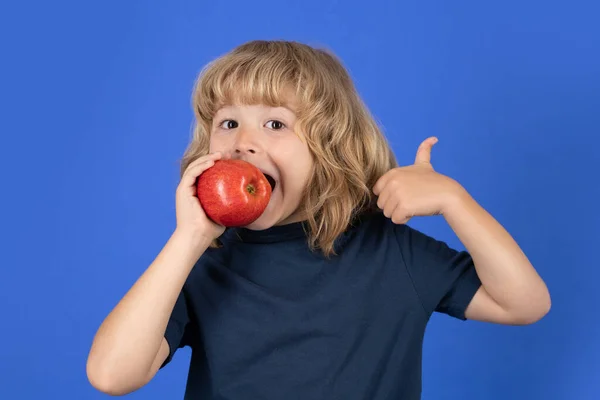Red apple. Little boy biting apple with fynny face. Kid eats healthy food