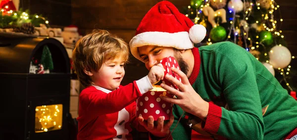 Daddy and son open Christmas gift. Father and son Wish you merry Christmas. Happy father and son in Santa hat with present have a Christmas at home