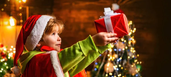 Child Boy Christmas Santa Hat Holds Gift Box Home Decorated — Stock Photo, Image