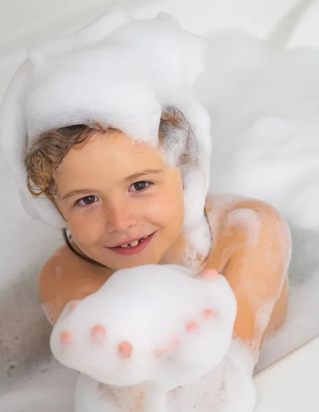 Kids face in foam. Kid bathing in a bath with foam. Funny kid face bathed in the bath