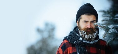 Karda sakallı ciddi bir adamın portresi. Karda sakallı kızgın bir kış adamı ciddi bir yüzle. Karlı sakallı kaba sakallı adam. Kışın karlı arka planda zalim hipster.