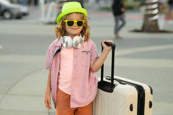 旅行中の子供たち 休暇中のスーツケース付きの子供 休日の観光少年は 旅行の子供の概念 街の通りの背景にスーツケース付きかわいい男の子 — ストック写真