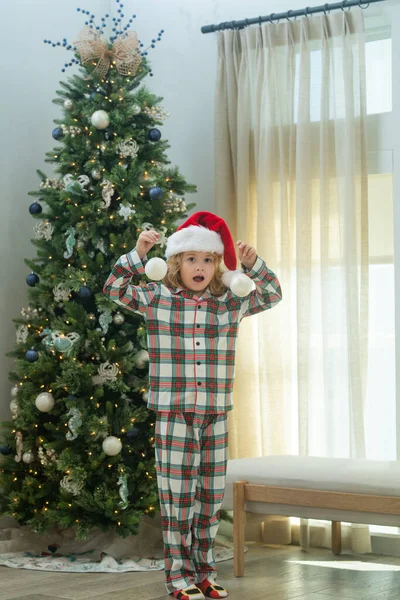 在家里的圣诞树旁 戴着圣诞礼帽的快乐孩子 — 图库照片