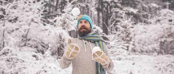 Funny man enjoying first snow. Winter funny man play with snow ball outdoor. Happy man walking in winter time. Winter game. Mam throws snowballs