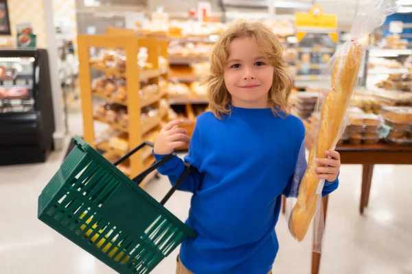 Kid is choosing fresh vegetables and fruits in the store. Child buying food in grocery supermarket. Buying in grocery store. Groceries in the supermarket