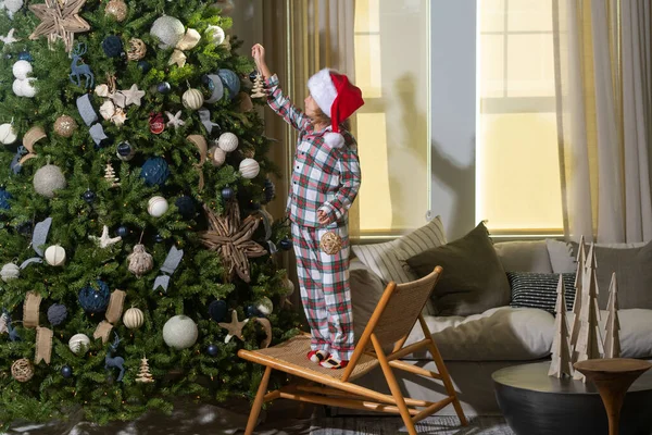 全长的快乐的孩子装饰圣诞树在家里 圣诞树旁戴着圣诞礼帽的快乐有趣的孩子 圣诞及新年概念 — 图库照片