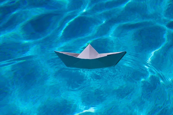Paper boat on the sea background. Origami paper boat sailing on water causing waves and ripples. Paper craft and origami
