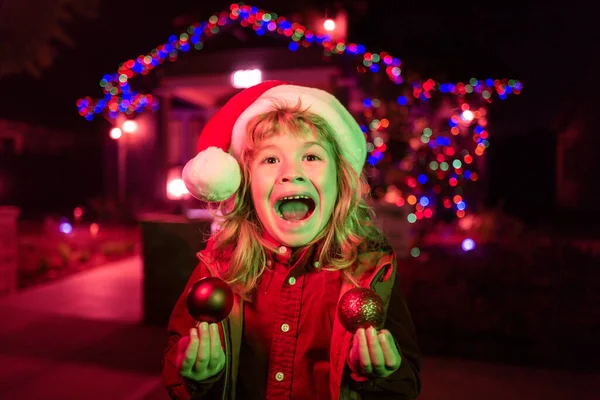 Happy New Year and merry Christmas. Excited kid in backyard of night house decorated for Christmas Eve celebration