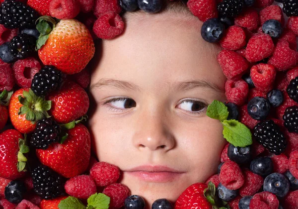 Funny fruits. Assorted mix of strawberry, blueberry, raspberry, blackberry background. Berries closeup near kids face. Fresh berries, top view. Mix of raw fresh berries fruits