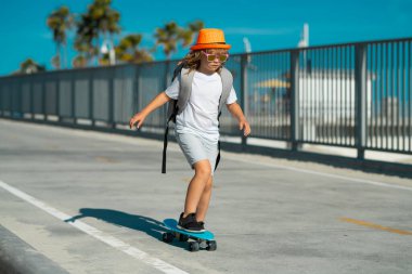 Yaz parkında kaykay yapan bir çocuk. Küçük çocuk kaykay yapmayı öğreniyor. Çocuklar için açık hava sporu. Çocuklar kaykay yapıyor. Çocuk kaykaya biniyor. Hadi gidelim. Kaykay yapan çocuk.