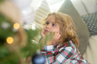 Mutlu çocuk evde Noel ağacının yanında. Kapalı portre, komik çocuk yüzü.