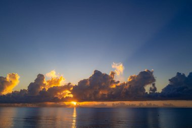 Gün batımı deniz manzarası. Sakin dalgalarla renkli sahil gündoğumu. Doğa deniz göğü. Mavi gökyüzüne ve denize karşı farklı renkte bulutlarla gün doğumu. Seyahat ve tatil arka planı, kopyalama alanı