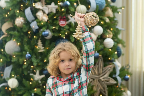 Little kid celebrating Christmas or New Year near Christmas tree at home