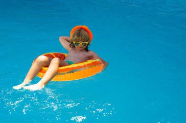 Çocuk havuzda dinleniyor. Çocuk su havuzunda yüzüyor. Yaz çocukları aktiviteleri, su sporları. Çocuklarla yaz tatili