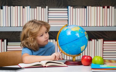 İlkokulun kütüphanesindeki küreye bakan bir öğrenci. İnek okulu çocuğu. İlkokuldan zeki bir çocuk. Zeki dahi zeki çocuk öğrenmeye hazır. Dünya küresi