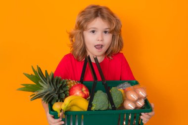 Yiyecek deposu. Sebze süpermarketindeki çocuk. Alışveriş sepetli çocuk. Çocuk markette ya da markette yiyecek seçiyor