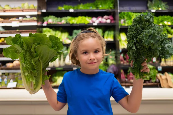 Kid with vegetables at grocery store. Funny cute child on shopping in supermarket. Grocery store. Grocery shopping, healthy lifestyle concept