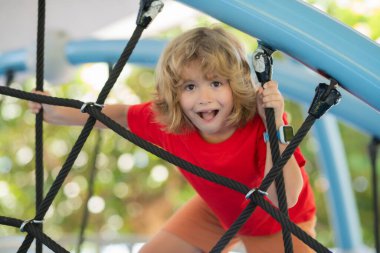 Açık hava çocuk parkı. Çocuk parkta oynuyor. Çocuk okulda ya da anaokulunda oynuyor. Çocuklar için sağlıklı bir yaz aktivitesi. Küçük çocuk oyun alanına tırmanıyor.
