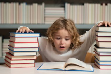 Kitap yığınları olan bir okul çocuğu. Bilgi toplama günü. Öğrenci kütüphanede kitap okuyor. Çocuklar okumayı öğrenir. Kitapçıda kitap okuyan bir çocuk