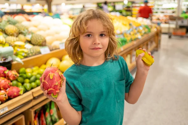 Kid with fruits. Kid is choosing fresh vegetables and fruits in the store. Child buying food in grocery supermarket. Buying in grocery store. Groceries in the supermarket