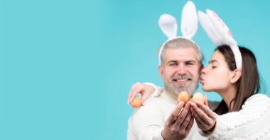 Paskalya için yumurtalı bir çift. Mavi arka planda tavşan kulaklı ve yumurtalı mutlu çift izole edildi. Tavşan kulaklı tavşan çift. Web sitesi başlık tasarımı için yatay fotoğraf pankartı