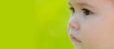 Baharda çim tarlasında bebek, afiş. Kafa bebek, yakın çekim. Çocuklar makro kesim yüz, küçük çocuk portresi