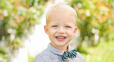 Close up face of cute child outdoors. Spring banner for website header. Sunny portrait of little boy. Spring smiling child. Happy childhood