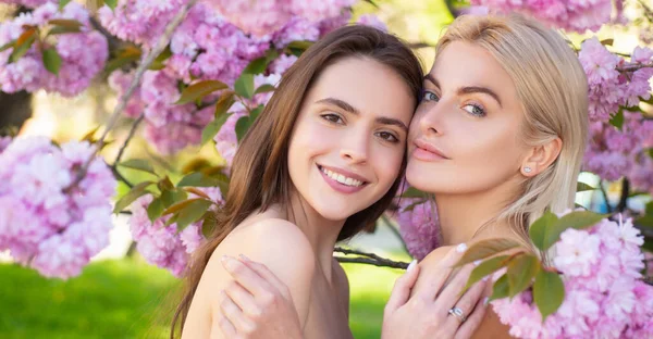 Sensual woman spring outdoor portrait banner. Smiling face of sensual girls. Beautiful young girls on blooming pink flowers. Natural makeup, lips, skin. Beauty and health. Spring nature
