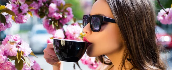 Woman drink coffee. Spring banner for website header. Good morning. Trendy drink latte matcha or mocha. Close up portrait of beautiful young woman hold cup of cofee with matcha