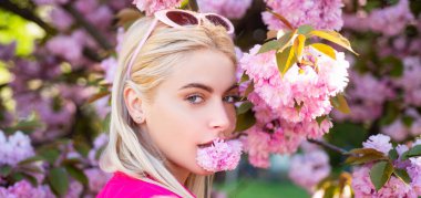 Sensual woman near sakura tree background, banner for website header. Beautiful girl in pink flowers in summer blossom park. Portrait of young woman in the flowered garden in the spring