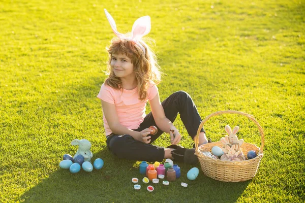 Easter bunny kids. Child boy in bunny Easter ears painting eggs. Cute little boy, easter bunny children spring outdoor