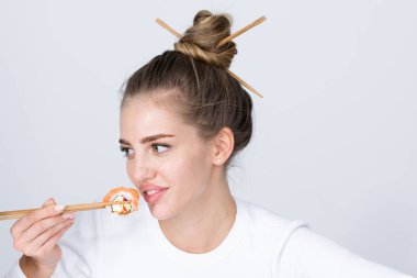 Suşi yiyen güzel seksi kadın. Suşi rulo, sashimi. Manken kız yemek çubuklarıyla suşi yiyor. Yemek çubuklarıyla saç kesimi, sağlıklı Japon yemekleri yemek.