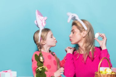 Mom with child girl are preparing for Easter. Mother and daughter wearing bunny ears are kissing. Easter banner, mockup copy space, poster flyer header for website template