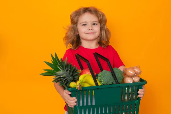 Child with grocery basket, isolated studio portrait. Concept of shopping at supermarket. Grocery shop. Shopping with grocery cart. Grocery store, shopping basket