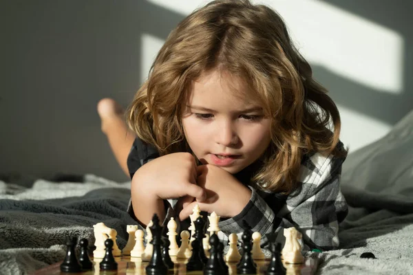 Chess school. Child think about chess game. Intelligent, smart and clever school kid pupil. Chess game with children at home