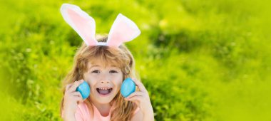 Bunny easter child. Kids hunting easter eggs. Boy with easter eggs and bunny ears in backyard Horizontal photo banner for website header design with copy space for text